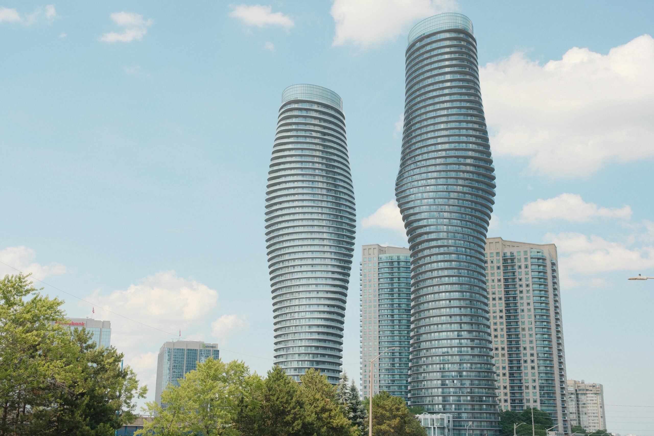 The iconic Absolute Towers of Mississauga, also known as the Marilyn Monroe Towers, against a bright blue sky.